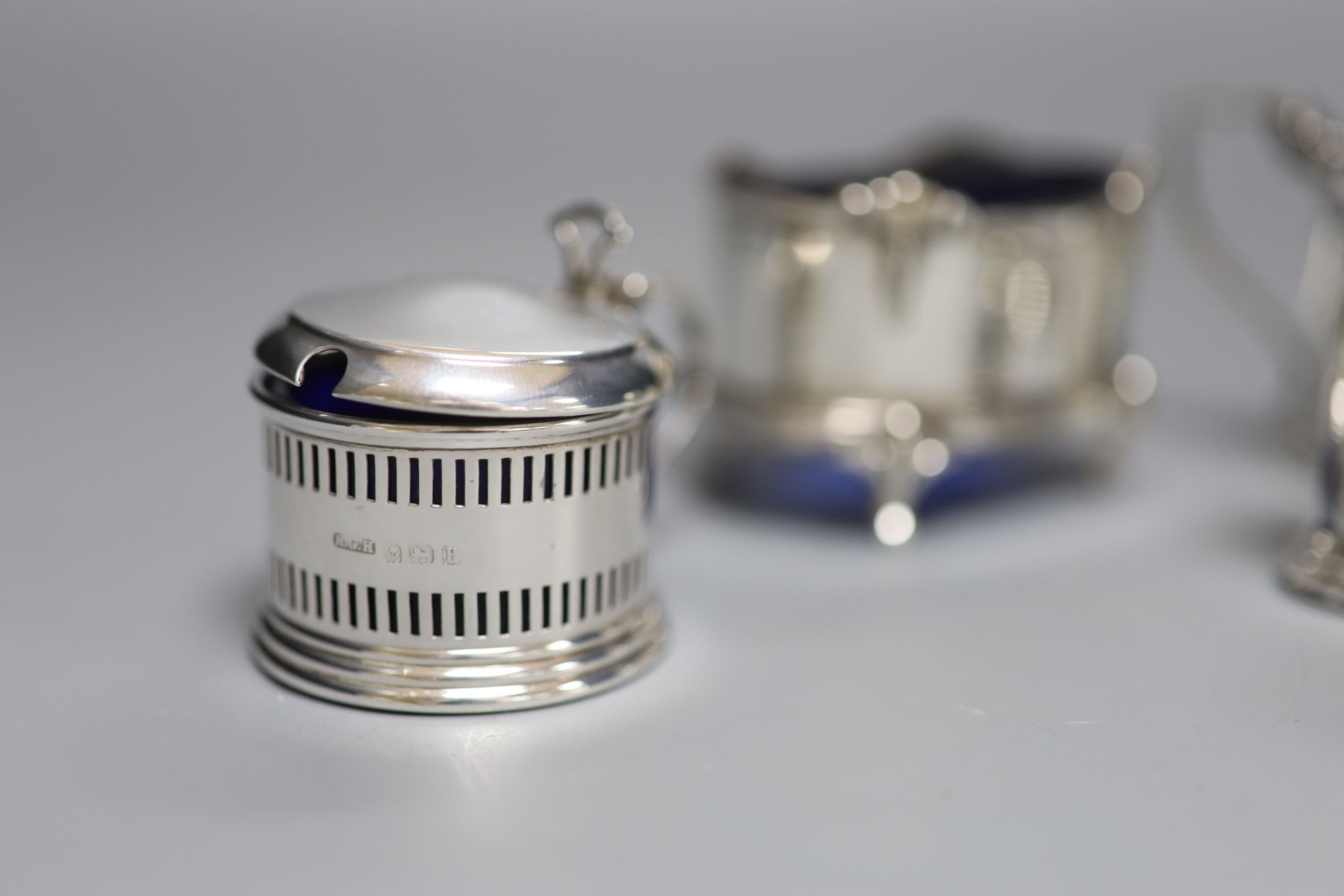 A George V small silver three piece condiment set, Birmingham, 1932 and two other silver condiments.